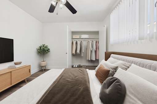 A bedroom with a large bed and a closet with clothes hanging.