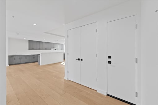 A white room with a wooden floor and two white doors.