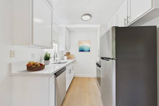 A kitchen with white cabinets and a black refrigerator.
