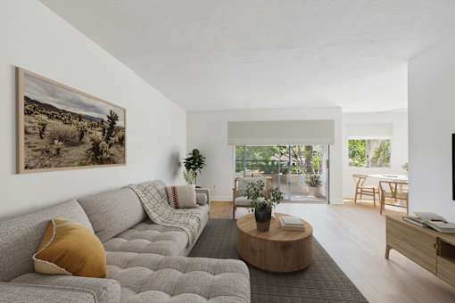 A living room with a grey couch and a painting on the wall.