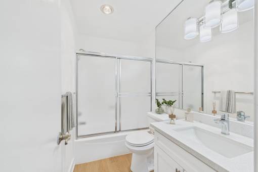 A white bathroom with a toilet, sink, and mirror.