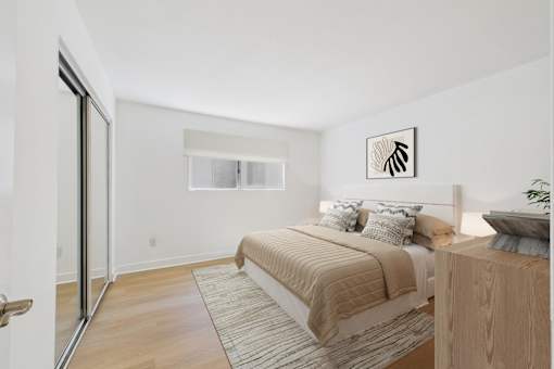 A bedroom with a bed, pillows, and a wooden nightstand.
