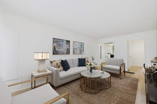 A living room with a white couch, a coffee table, and a painting on the wall.