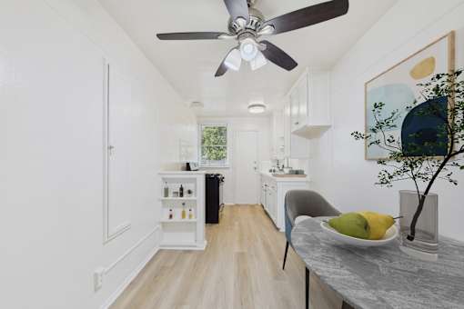 A modern kitchen with a dining table and a ceiling fan.