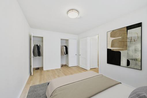 A room with a bed, a wardrobe and a painting on the wall.