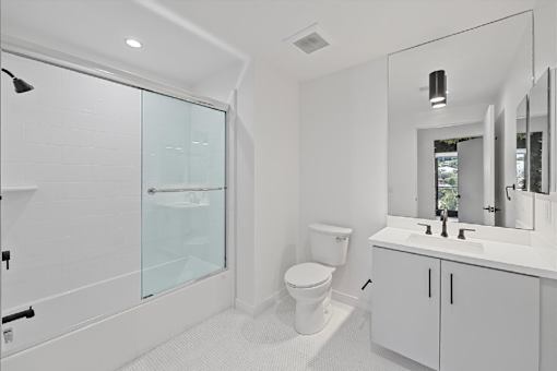 A white bathroom with a toilet, sink, and shower.