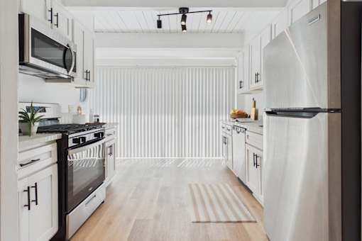 A modern kitchen with white cabinets and stainless steel appliances.