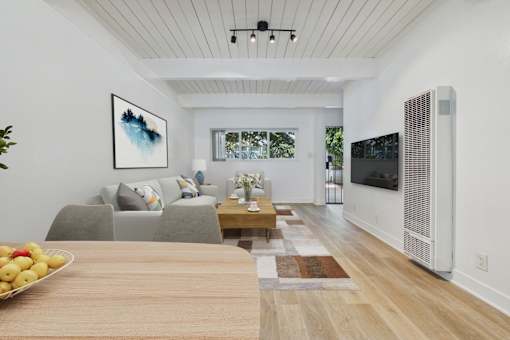 A modern living room with a grey couch, a wooden table, and a painting on the wall.