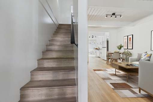 A staircase with a wooden tread and riser leads to a living room.