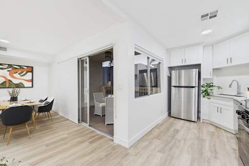 A kitchen with a refrigerator, sink, and dining table.