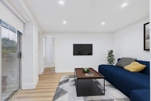 A modern living room with a blue couch and a flat screen TV mounted on the wall.