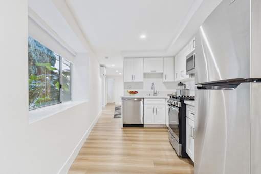 A modern kitchen with white appliances and wooden floors.