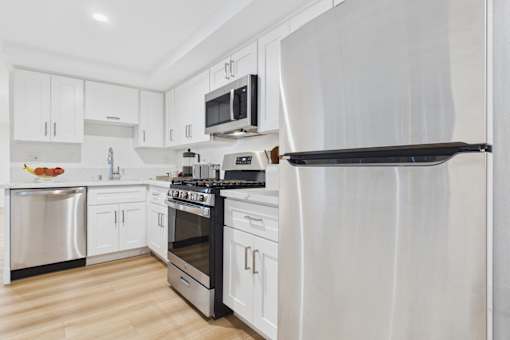 A modern kitchen with a refrigerator, oven, and microwave.