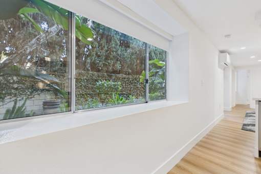 A long hallway with a window overlooking a lush green garden.