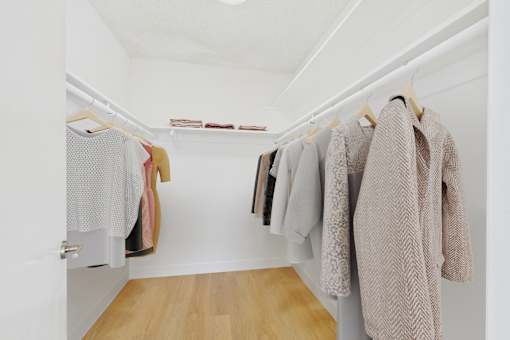 A row of clothes hanging on a rack in a white room.