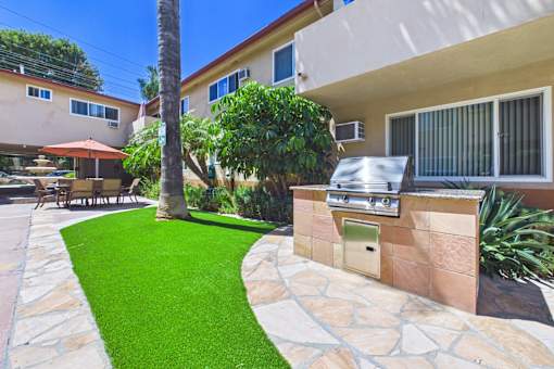 A backyard with a stone wall and a green lawn.