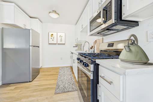 A kitchen with a stove, refrigerator, and microwave.