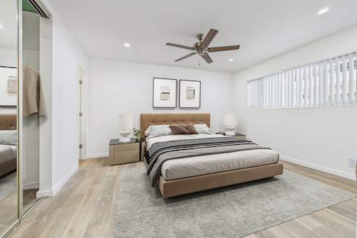 A bedroom with a large bed and a ceiling fan.