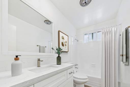 A white bathroom with a toilet, sink, and shower.