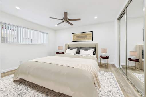 A bedroom with a large bed and a ceiling fan.
