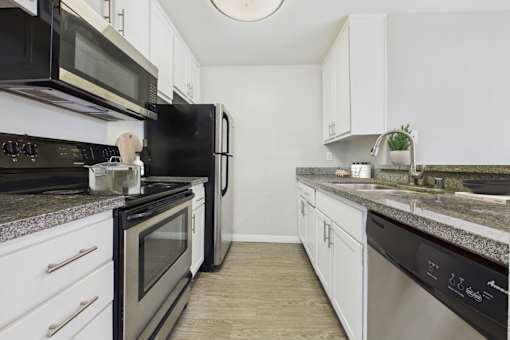 A kitchen with black appliances and white cabinets.