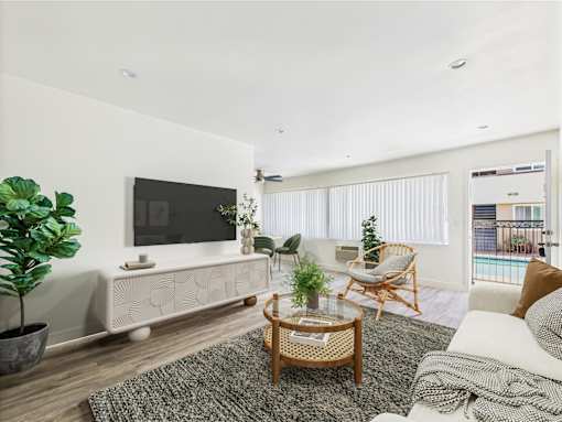 A modern living room with a television, a chair, a table, and a potted plant.