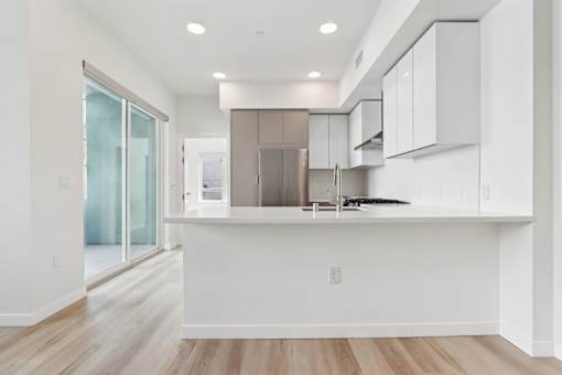 A modern kitchen with white cabinets and a wooden floor.