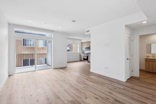 A spacious room with wooden flooring and white walls.
