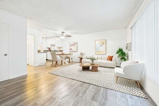 A living room with a white couch, a coffee table, and a dining table with chairs.