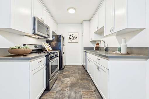 A kitchen with white cabinets and a black refrigerator.