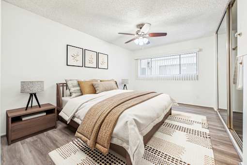 A bedroom with a bed, a ceiling fan, and a rug.