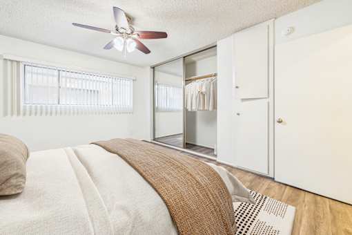 A bedroom with a bed, a ceiling fan, and a closet.