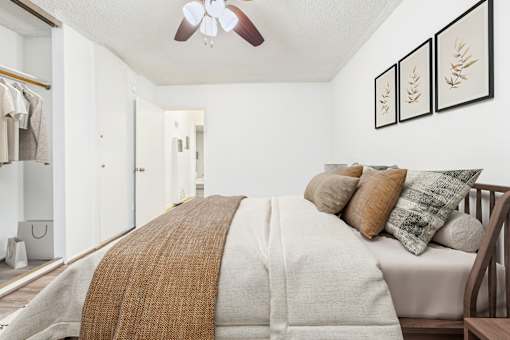 A bedroom with a bed covered in a white comforter and a brown throw.