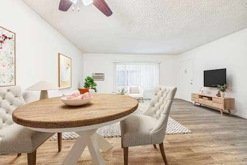 A living room with a round wooden table and chairs.