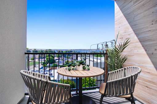 A balcony with a table and two chairs overlooking a street.