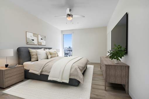A bedroom with a bed, nightstand, and a ceiling fan.