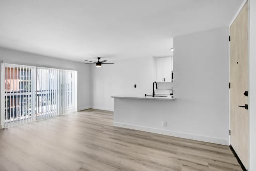 an empty living room with a kitchen and a balcony