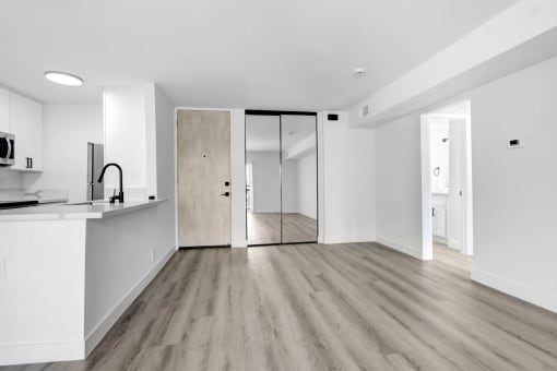 an empty living room with a kitchen and a sliding glass door