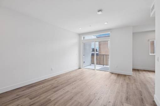 A room with wooden flooring and white walls.