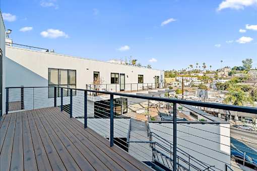 A balcony with a wooden floor overlooks a city street.