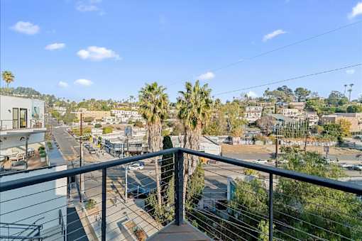 A balcony overlooks a street with cars and houses.