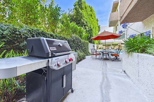 A black grill is on a patio with a table and chairs.