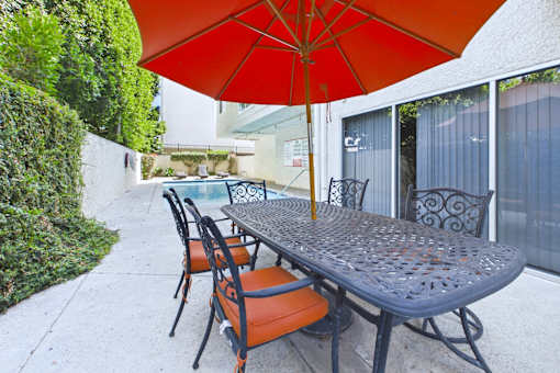 A table with chairs and an umbrella is on a patio.