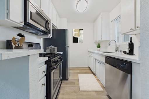 A modern kitchen with black appliances and white cabinets.