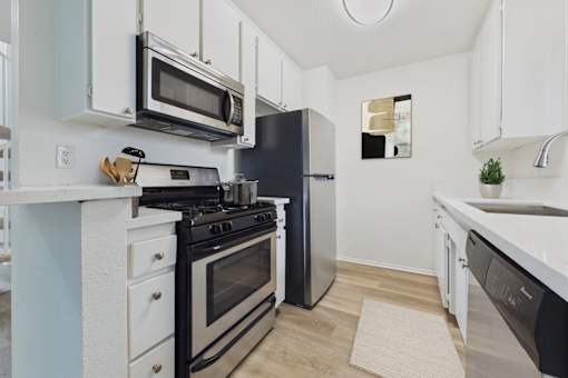 A modern kitchen with black and white appliances and wooden floors.