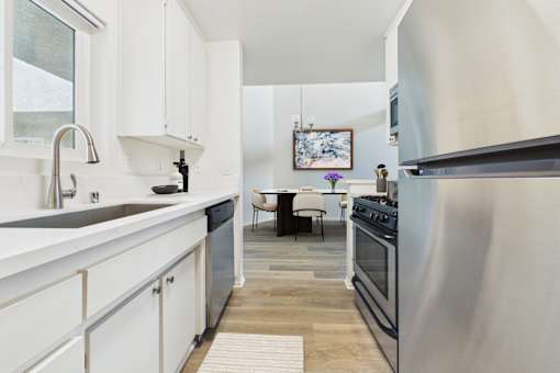 A modern kitchen with white cabinets and a wooden floor.
