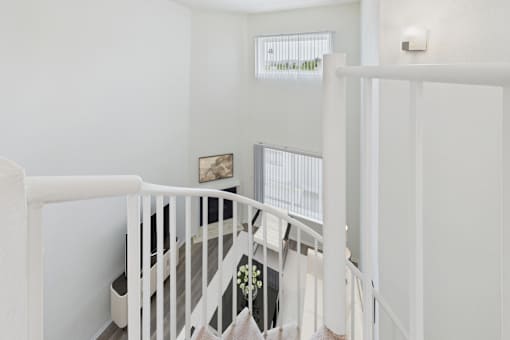 A white staircase with a white railing and a small picture on the wall.