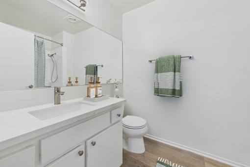 A white bathroom with a toilet, sink, and a mirror.