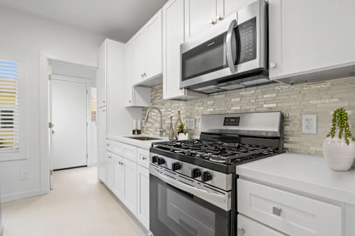 A modern kitchen with white cabinets and a black stove top.