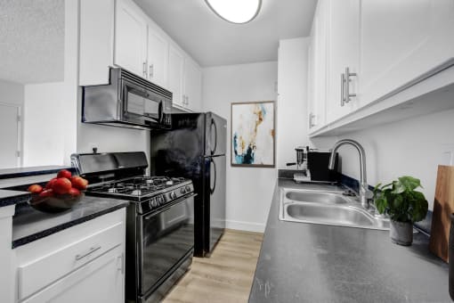 a modern kitchen with black appliances and white cabinets